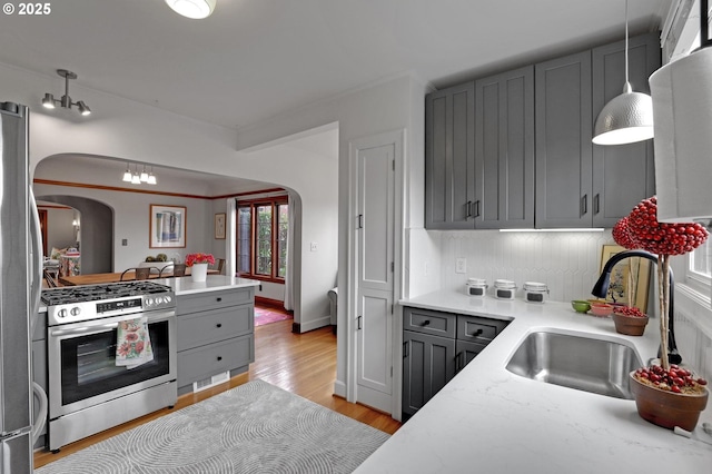 kitchen featuring stainless steel appliances, arched walkways, and gray cabinetry