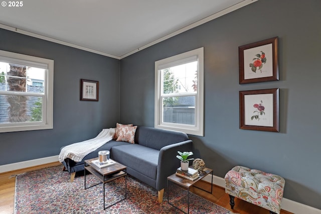 living area with baseboards, wood finished floors, and crown molding