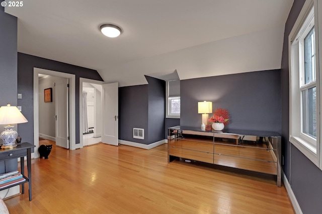 bedroom with visible vents, baseboards, lofted ceiling, and light wood finished floors