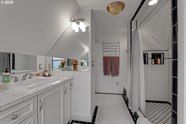 bathroom featuring tile patterned flooring, baseboards, vaulted ceiling, tiled shower, and vanity