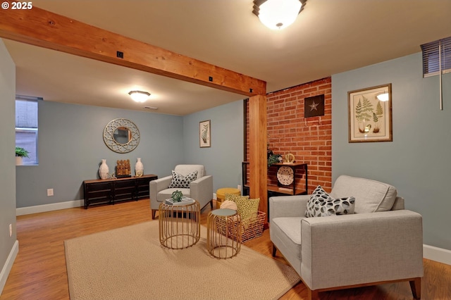 living area featuring beamed ceiling, baseboards, visible vents, and wood finished floors