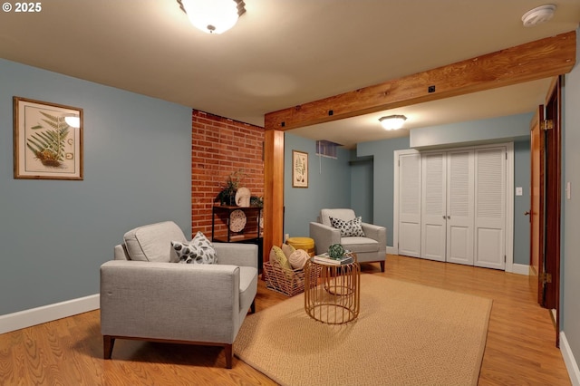 sitting room featuring visible vents, beamed ceiling, light wood-style floors, and baseboards