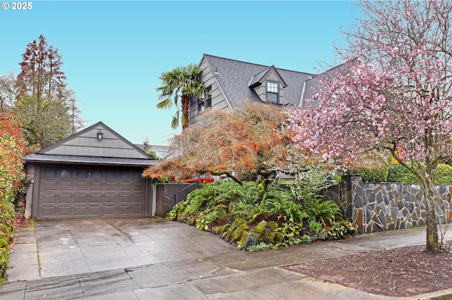 view of front of home featuring a garage, roof with shingles, and fence