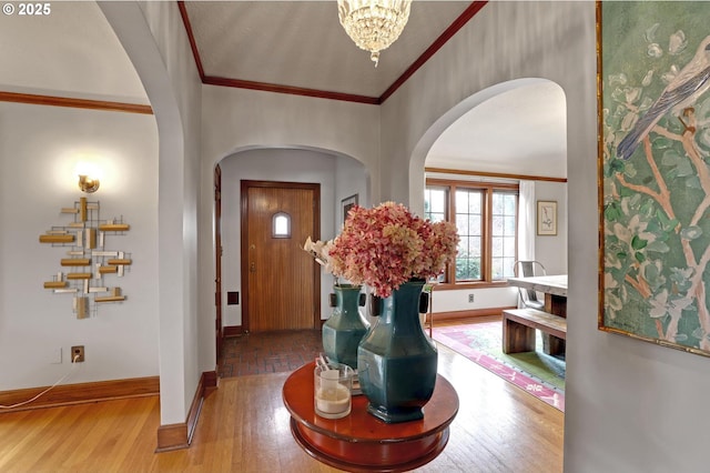 entryway with arched walkways, wood finished floors, and crown molding