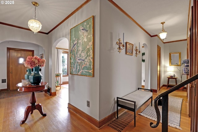 entrance foyer featuring crown molding, wood finished floors, arched walkways, and baseboards