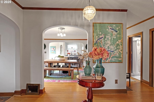 entryway featuring arched walkways, a notable chandelier, visible vents, and wood finished floors