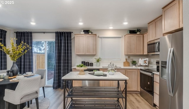 kitchen featuring light brown cabinetry, appliances with stainless steel finishes, a sink, light wood-style floors, and light countertops