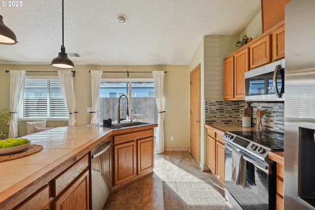 2383 SE 61st Ln, Hillsboro, OR 97123 - kitchen with stainless steel appliances, tile counters, a sink, decorative backsplash, and a textured ceiling