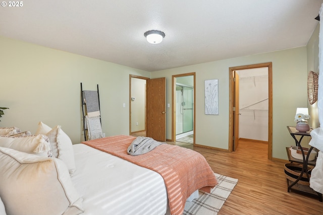 2383 SE 61st Ln, Hillsboro, OR 97123 - bedroom featuring a walk in closet, light wood-style flooring, a closet, baseboards, and connected bathroom