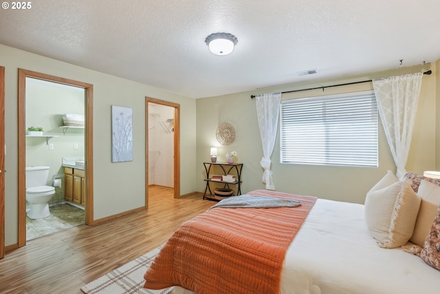 2383 SE 61st Ln, Hillsboro, OR 97123 - bedroom with light wood-style flooring, a textured ceiling, ensuite bathroom, and baseboards