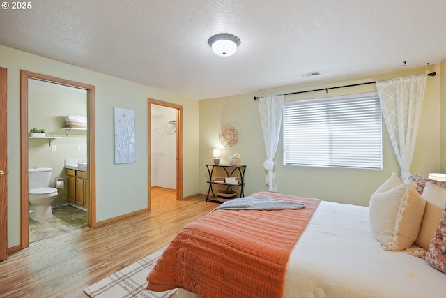2383 SE 61st Ln, Hillsboro, OR 97123 - bedroom with light wood finished floors, a textured ceiling, ensuite bathroom, and baseboards