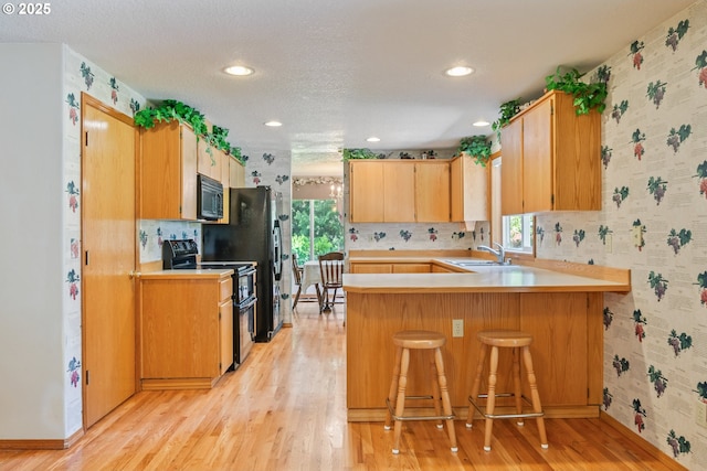 230 S Maple Hill Rd, Kelso, WA 98626 - kitchen with black appliances, a sink, light countertops, wallpapered walls, and light wood finished floors
