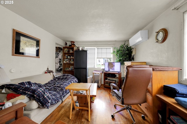 bedroom featuring radiator, an AC wall unit, a textured ceiling, and wood finished floors