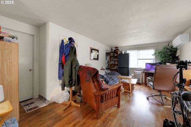 interior space featuring light wood-type flooring, radiator heating unit, a textured ceiling, and a wall mounted air conditioner