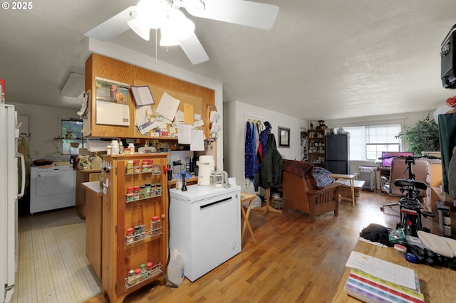 kitchen featuring light countertops, light wood-style flooring, freestanding refrigerator, washer / dryer, and fridge