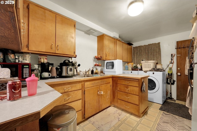 kitchen with brown cabinets, washer / clothes dryer, light countertops, and a sink