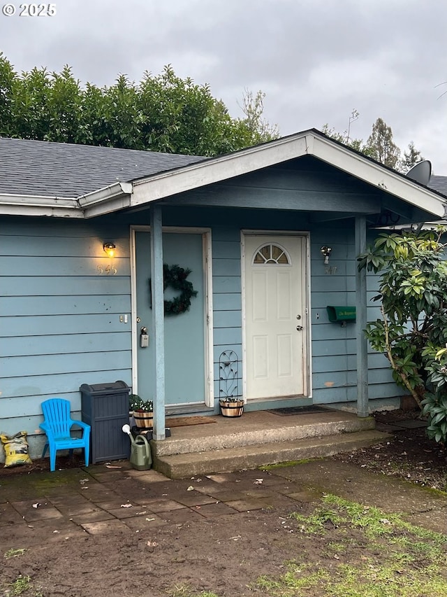 view of exterior entry with roof with shingles