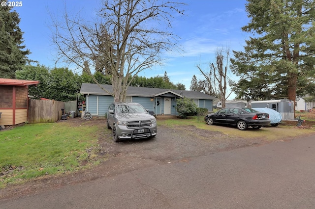 ranch-style house with driveway, a front lawn, and fence