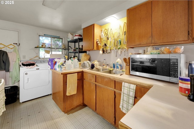 kitchen featuring light countertops, stainless steel microwave, brown cabinetry, a sink, and washer / dryer