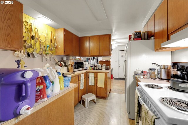 kitchen featuring brown cabinets, electric stove, light countertops, and stainless steel microwave