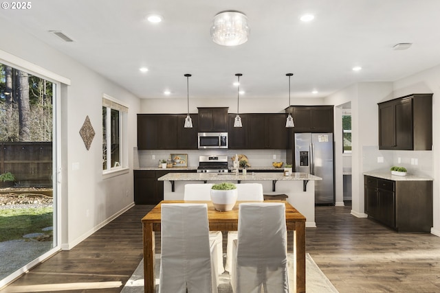 kitchen featuring dark hardwood / wood-style floors, dark brown cabinetry, appliances with stainless steel finishes, and decorative light fixtures