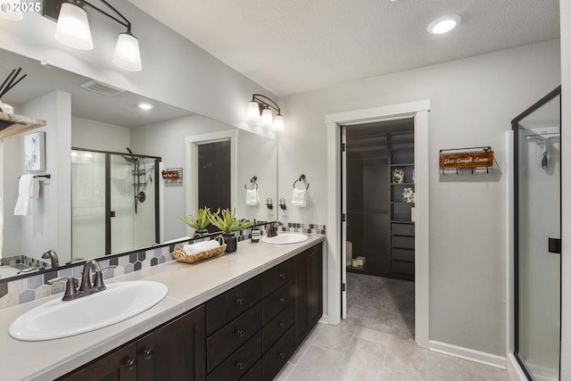 bathroom with walk in shower, tile patterned floors, vanity, and a textured ceiling