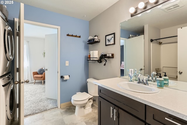 bathroom with vanity, toilet, and stacked washing maching and dryer