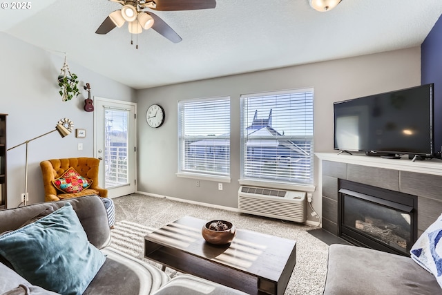 living room featuring a wall mounted air conditioner, lofted ceiling, carpet floors, a tiled fireplace, and ceiling fan