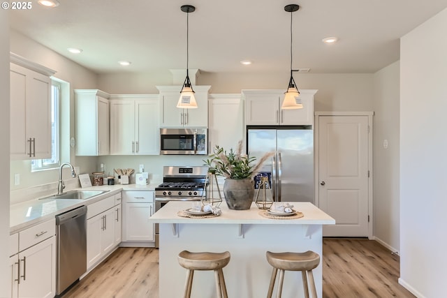 11331 NW Main St, North Plains, OR 97133 - kitchen featuring appliances with stainless steel finishes, a sink, a center island, light wood-type flooring, and light countertops