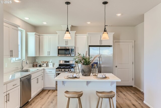 11331 NW Main St, North Plains, OR 97133 - kitchen with appliances with stainless steel finishes, a sink, a kitchen island, light wood-style floors, and light countertops