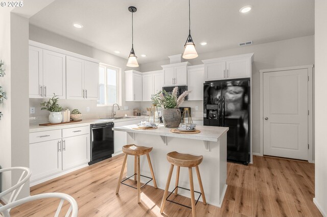 11331 NW Main St, North Plains, OR 97133 - kitchen with black appliances, a sink, white cabinets, light countertops, and a breakfast bar area