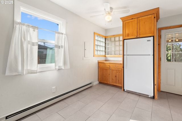 kitchen featuring light tile patterned floors, a baseboard radiator, plenty of natural light, and white fridge