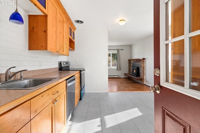 kitchen featuring pendant lighting, sink, stainless steel appliances, a fireplace, and a baseboard radiator