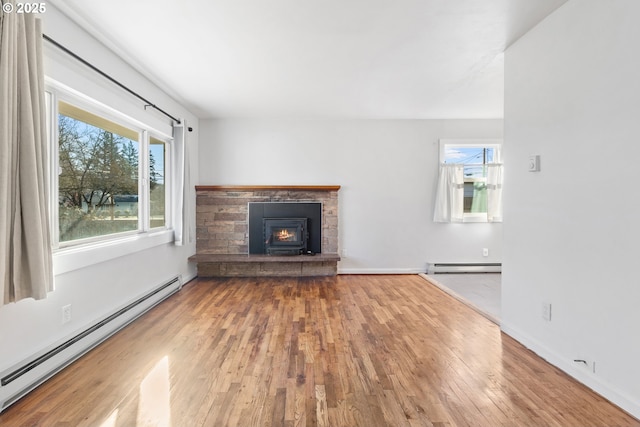 unfurnished living room featuring hardwood / wood-style flooring, a wealth of natural light, and a baseboard heating unit