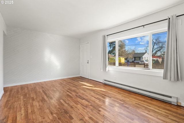 empty room featuring hardwood / wood-style flooring and a baseboard radiator