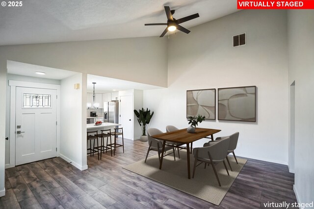 unfurnished living room with ceiling fan with notable chandelier, high vaulted ceiling, and dark hardwood / wood-style floors