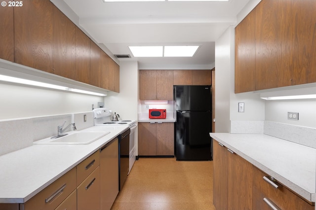 kitchen with white range with electric cooktop, a sink, freestanding refrigerator, brown cabinetry, and light floors