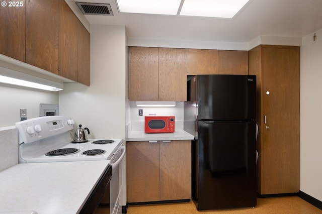 kitchen with brown cabinetry, visible vents, electric range, freestanding refrigerator, and light countertops