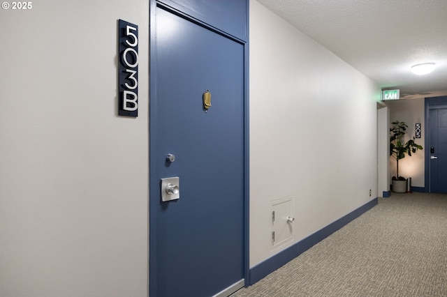 hallway with baseboards, a textured ceiling, and carpet flooring