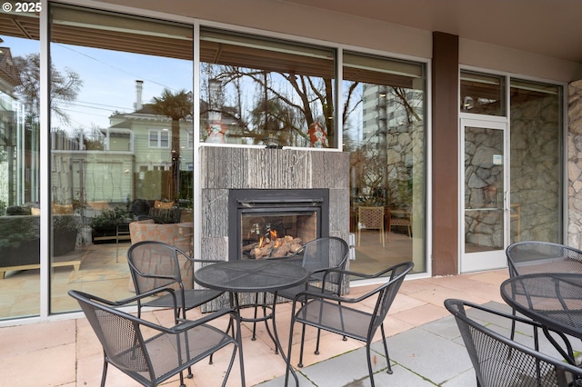 view of patio featuring a warm lit fireplace and outdoor dining space