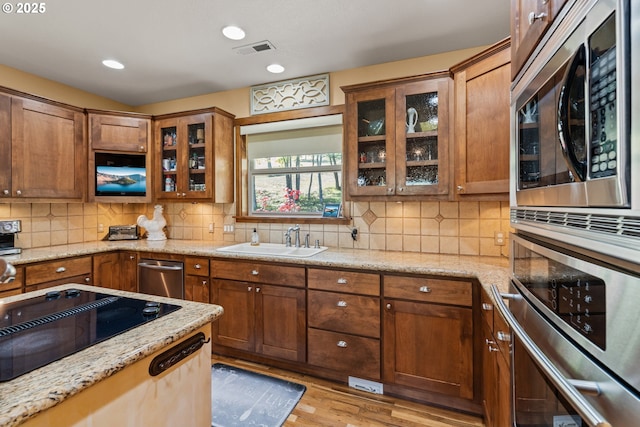 2809 Dead Indian Memorial Rd, Ashland, OR 97520 - kitchen featuring light stone countertops, light wood-style floors, tasteful backsplash, a sink, and stainless steel appliances