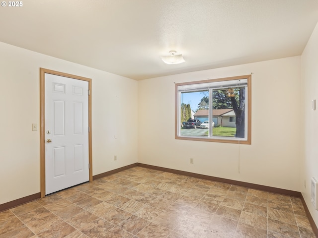 spare room with baseboards and stone finish floor