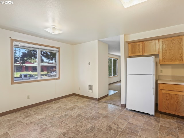 kitchen with baseboards, a healthy amount of sunlight, and freestanding refrigerator