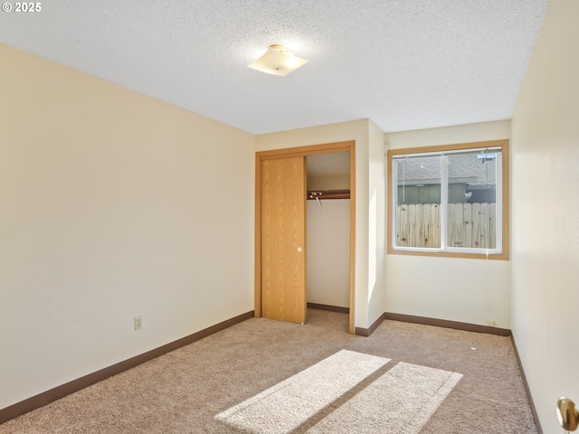 unfurnished bedroom with a closet, baseboards, a textured ceiling, and carpet flooring