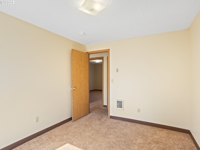 carpeted spare room featuring visible vents, a textured ceiling, and baseboards