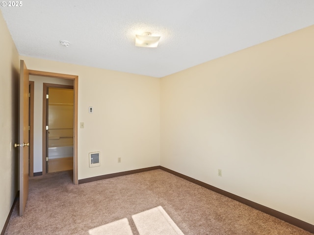 carpeted spare room featuring a textured ceiling and baseboards