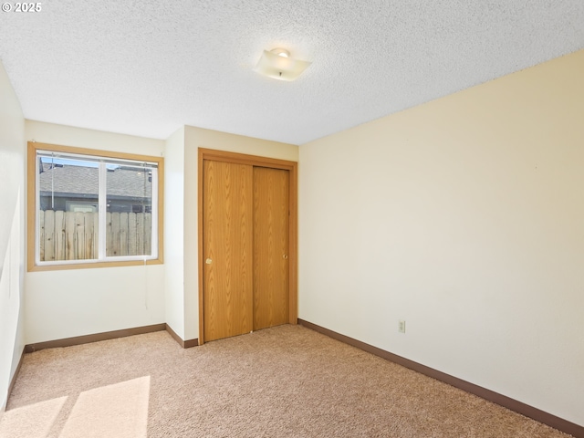 unfurnished bedroom featuring a closet, carpet floors, a textured ceiling, and baseboards