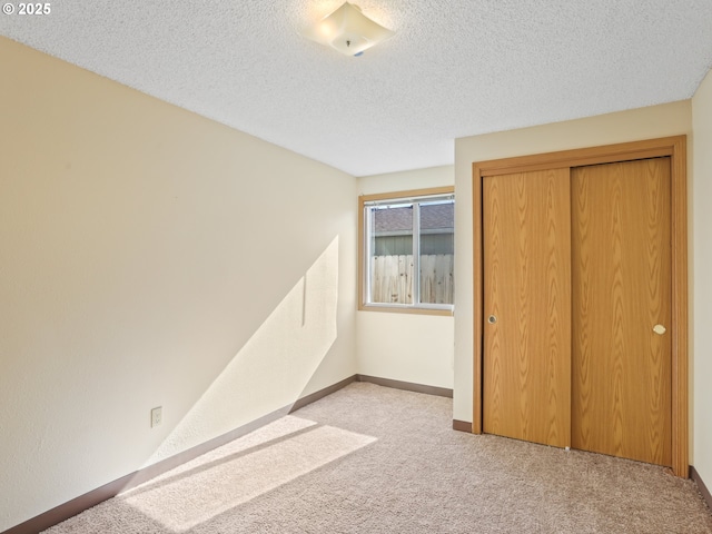 unfurnished bedroom with a closet, carpet flooring, a textured ceiling, and baseboards