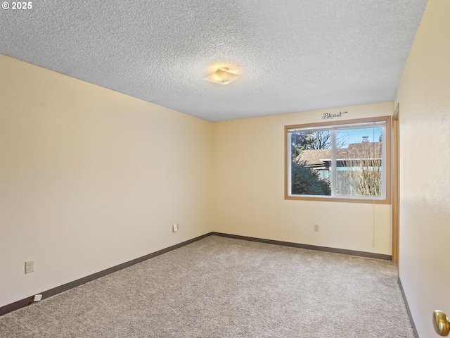 empty room featuring carpet flooring, a textured ceiling, and baseboards