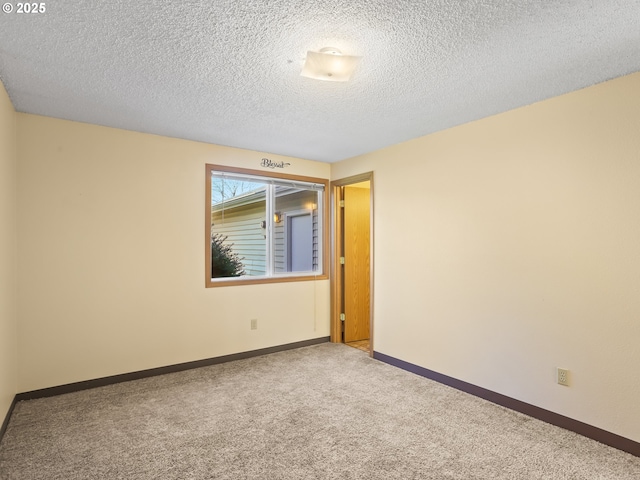 spare room with carpet flooring, a textured ceiling, and baseboards